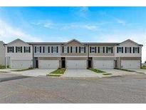 Row of modern townhomes showcasing attached garages and neutral color palettes on a sunny day at 8656 Webb Rd, Riverdale, GA 30274