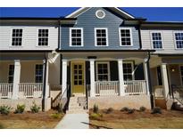 Charming townhouse featuring a welcoming porch, brick accents, and a vibrant yellow front door at 316 Oak Arms Way, Woodstock, GA 30188