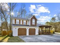 Charming two-story home with two-car garage, stone accents, covered porch, and mature trees at 10846 Sunfield Way, Hampton, GA 30228