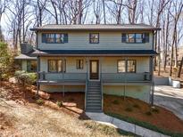 Two-story home featuring a covered front porch, neutral siding, updated windows, and landscaped yard at 117 Holt Ne Rd, Marietta, GA 30068