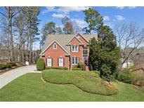 Charming red brick home with manicured lawn, mature trees, and inviting curb appeal at 340 Ruby Forest Pkwy, Suwanee, GA 30024