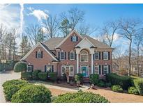 Charming brick home featuring a manicured lawn, lush landscaping, and a welcoming light blue front door at 6195 Mountainwell Dr, Roswell, GA 30075