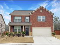 Charming two-story brick home featuring a well-manicured lawn, shutters, and an attached two-car garage at 3062 Hawthorn Farm Blvd, Loganville, GA 30052