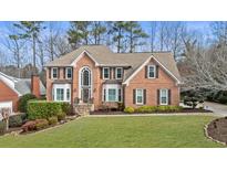 Charming two-story brick home with well-manicured lawn, mature landscaping, and elegant entrance at 4155 Park Brooke Dr, Alpharetta, GA 30022