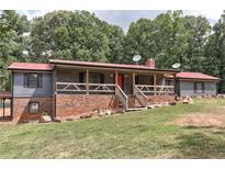Charming home featuring a red metal roof, brick foundation, front porch, and a front yard with mature trees at 616 Rich Davis Rd, Hiram, GA 30141