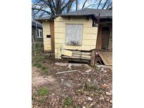 A deteriorated yellow home with boarded windows and visible damage to the siding and foundation at 1771 Hosea L Williams Se Dr, Atlanta, GA 30317