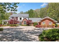 Elegant brick home with a circular driveway and lush landscaping at 1790 Mountain Farm Rd, Woodstock, GA 30188