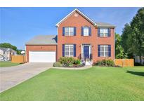 Inviting two-story brick home featuring a well-manicured lawn and attached two-car garage at 5760 Stephens Mill Dr, Sugar Hill, GA 30518