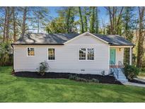 Charming one-story home with a well-maintained lawn, landscaping, and a pop of color on the front door at 2740 Dale Creek Nw Dr, Atlanta, GA 30318