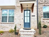 Charming brick home featuring a stylish blue front door with decorative wood accents at 3255 Bartee Walk, Suwanee, GA 30024