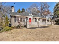 Charming brick home featuring a bright red door, classic shutters, and a welcoming white picket fence at 1883 Rugby Ave, Atlanta, GA 30337