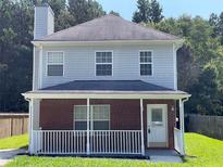 Charming two-story home featuring gray siding, a brick porch, and a well-manicured lawn at 5642 Feldwood Rd, Atlanta, GA 30349