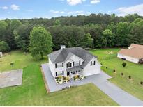 Inviting two-story home with a well-manicured lawn and a basketball court is nestled in a serene wooded setting at 709 Mohansic Ave, Loganville, GA 30052