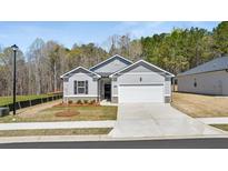 Charming single-story home featuring a gray exterior, attached garage, and landscaped front yard at 8592 Secretariat Dr, Lithonia, GA 30058