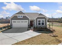 Charming craftsman-style home with gray siding, stone accents, a two-car garage, and a well-manicured front yard at 144 Laurel Farms Ln, Dallas, GA 30157