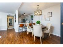 Inviting dining area featuring a stylish light fixture and seating, complemented by a modern kitchen and hardwood floors at 407 Brighton Pt, Atlanta, GA 30328