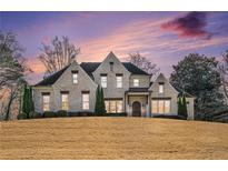 Elegant brick home featuring a well-manicured lawn and a picturesque sunset sky at 1005 W Kingston Dr, Atlanta, GA 30342