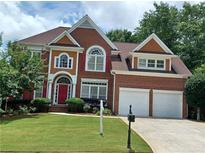 Beautiful two-story brick home with a well-manicured lawn, two car garage, and red shutters on the windows at 3302 Fieldwood Se Dr, Smyrna, GA 30080