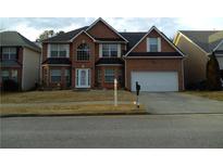 Two-story brick home features a two-car garage and a manicured front lawn at 1975 Lily Stem Trl, Auburn, GA 30011