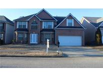 Charming two-story brick home features a two-car garage, well-maintained lawn, and inviting front entrance at 1975 Lily Stem Trl, Auburn, GA 30011