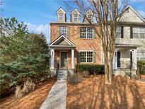 Charming brick townhome featuring dormer windows and landscaped front yard under a clear blue sky at 1100 Cotton Gin Dr, Woodstock, GA 30188
