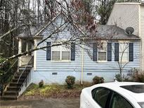 Charming home featuring a blue exterior, complemented by black shutters and a well-maintained front yard at 2041 Marbut Trce, Lithonia, GA 30058