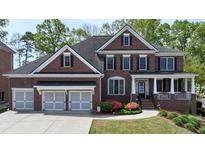 Charming brick home featuring a manicured lawn, inviting porch, and a spacious three-car garage at 2875 Ivy Brook Ln, Buford, GA 30519