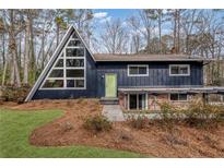 Striking A-frame home featuring a unique window design, dark siding, and a charming green front door at 3894 Foxford Dr, Atlanta, GA 30340