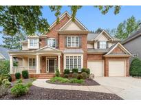 Beautiful brick home with a manicured front yard, covered porch, and two-car garage at 625 Jefferson Pl, Cumming, GA 30040