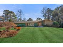 Expansive front yard featuring lush lawn and mature trees framing a single-story home at 2584 Regency W Dr, Tucker, GA 30084