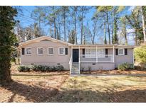 Charming brick home with a covered front porch and manicured lawn and mature trees at 1945 Dodson Sw Dr, Atlanta, GA 30311