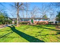 Charming single-story home featuring a lush lawn, mature trees, and a covered carport at 399 Talcott Nw Cir, Marietta, GA 30064