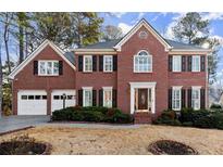 Stately brick home with a two-car garage, manicured landscaping and classic shutters at 1303 Crooked Branch Trl, Woodstock, GA 30189