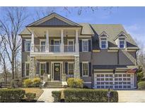 Charming two-story home featuring a welcoming front porch, stone accents, and manicured landscaping at 4815 Westgate Dr, Cumming, GA 30040