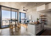 Bright living room features concrete walls, a ceiling fan, and a balcony with city views at 480 John Wesley Dobbs Ne Ave # 810, Atlanta, GA 30312