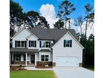 Charming two-story home featuring a manicured lawn, attached garage, and neutral color palette against a backdrop of lush trees at 5975 Crowley Dr, Douglasville, GA 30135