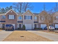 Townhome exterior showing a well-kept lawn and driveways leading to attached garages at 151 Creekwood Dr, Woodstock, GA 30188