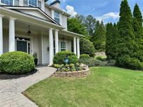 Charming home featuring manicured landscaping, lush green lawn, and a welcoming front porch with classic columns at 200 Edinburgh Ln, Woodstock, GA 30188
