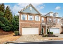 Charming brick townhome with a two-car garage and manicured landscaping on a beautiful day at 3557 Ashcroft Se Dr, Smyrna, GA 30080