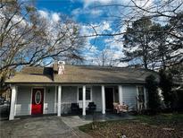Charming single-story home with gray siding, red door, inviting front porch, and mature trees in a serene neighborhood at 3356 Hollow Ct, Lawrenceville, GA 30044