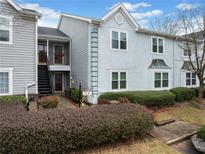 Charming two-story condo featuring landscaped front yard, gray siding, and exterior staircase to the upper level at 14 Hampshire Ct, Avondale Estates, GA 30002