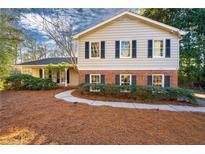 Charming home features a mix of brick and siding, complemented by dark shutters and a well-manicured front yard at 1105 Orchard Way, Roswell, GA 30075