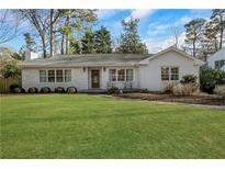 Charming brick home with a well-manicured front lawn, mature trees, and a cozy, inviting appeal at 834 Kipling Nw Dr, Atlanta, GA 30318