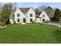 Stunning exterior elevation of a home with a manicured lawn, arched entry, and detailed trim work at 1297 Swims Valley Nw Dr, Atlanta, GA 30327