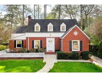 Charming brick home with a well-manicured lawn, white picket fence, and inviting walkway at 1772 Meadowdale Ne Ave, Atlanta, GA 30306