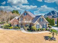 Stunning two-story home featuring a manicured lawn, stone accents, and a welcoming front porch at 955 Golf View Ct, Dacula, GA 30019