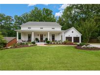 Charming white farmhouse with inviting front porch, lush lawn, and detached two-car garage at 443 Westside Dr, Roswell, GA 30075