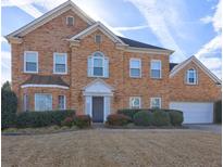 Charming brick home showcasing a well-maintained lawn, mature landscaping and attached garage at 1225 Sand Knoll Sw Run, Lilburn, GA 30047