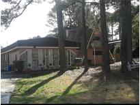 Quaint house exterior with unique architecture and natural stone accents, surrounded by mature trees in a serene setting at 6774 Collier Rd, Riverdale, GA 30296