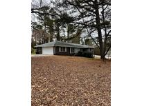 Charming brick home with an attached garage, mature trees, and a lush front yard, inviting and well-maintained at 2580 Lake Capri Road Northwest, Conyers, GA 30012